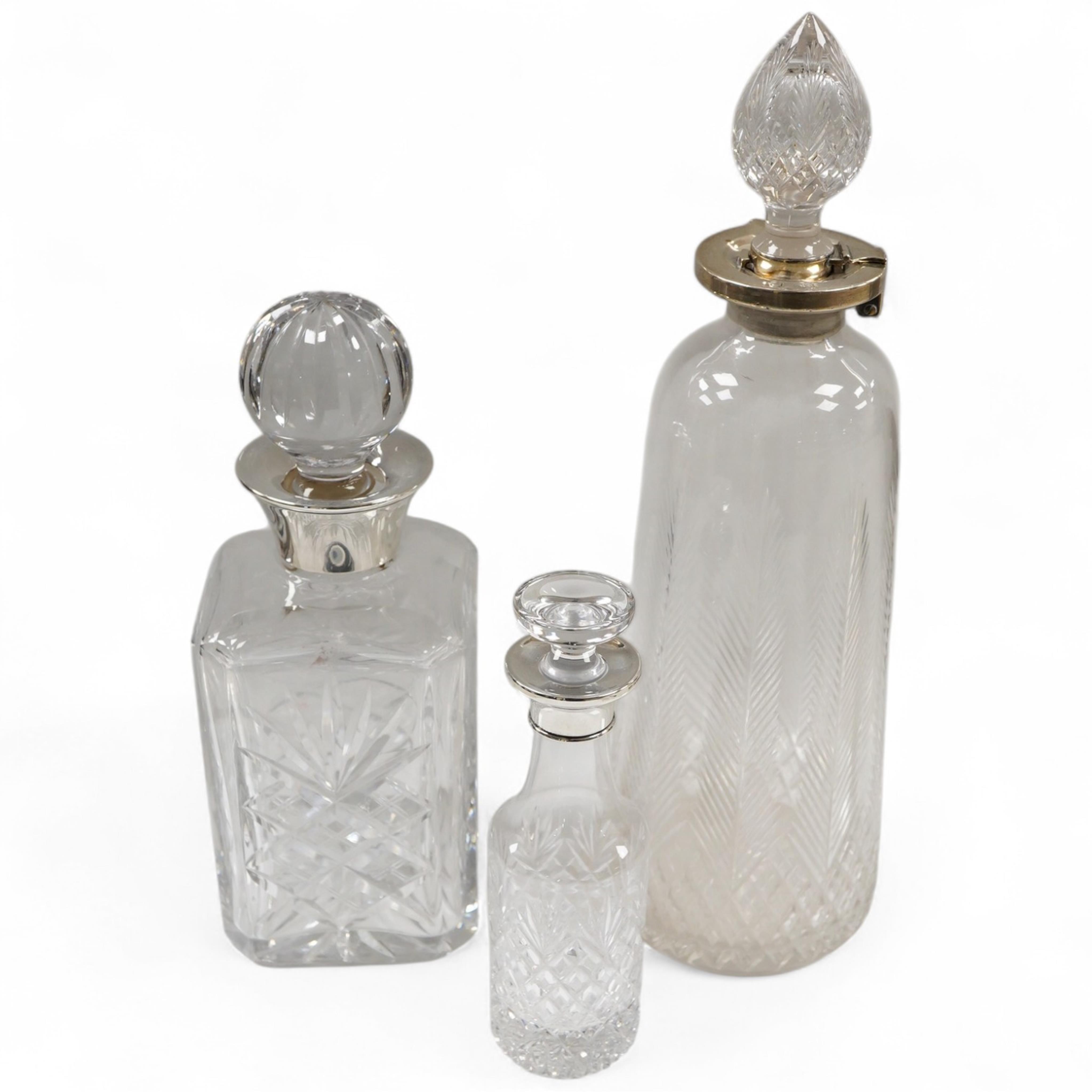 Three assorted silver mounted cut glass decanters, including two modern and one earlier with lock, marks rubbed, no key, the latter 34.1cm.